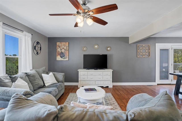 living room featuring beam ceiling, hardwood / wood-style flooring, and ceiling fan