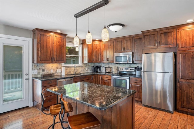 kitchen featuring light hardwood / wood-style floors, appliances with stainless steel finishes, sink, and a kitchen island