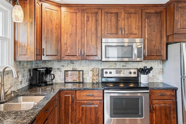 kitchen featuring sink, stainless steel appliances, backsplash, and dark stone countertops