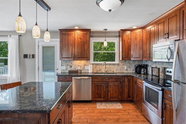 kitchen with light hardwood / wood-style floors, stainless steel appliances, sink, and pendant lighting