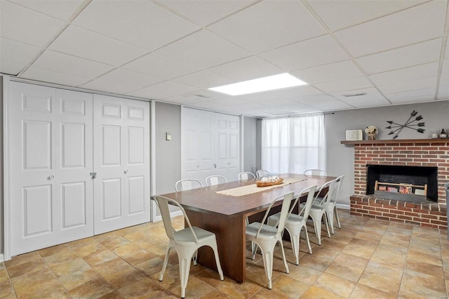 dining room with a paneled ceiling and a brick fireplace