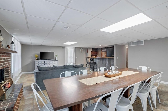 dining room featuring a drop ceiling and a fireplace