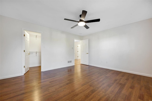 unfurnished bedroom with a walk in closet, ceiling fan, and dark hardwood / wood-style floors