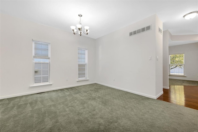 carpeted spare room with an inviting chandelier