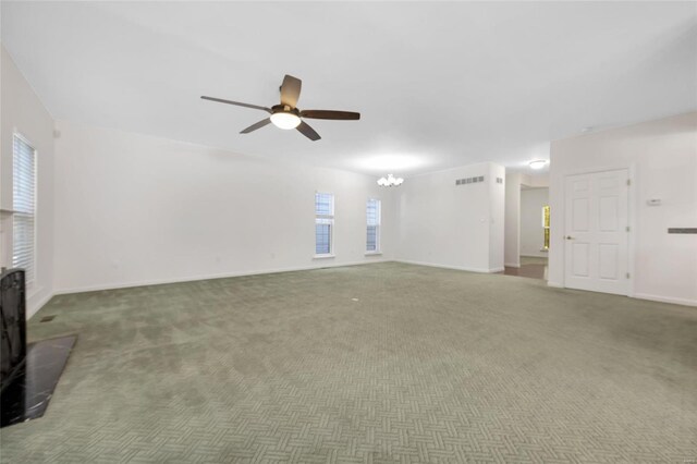 unfurnished living room with ceiling fan with notable chandelier and dark colored carpet