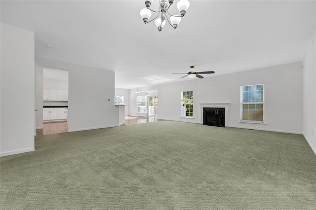 unfurnished living room featuring ceiling fan with notable chandelier, a premium fireplace, and carpet floors