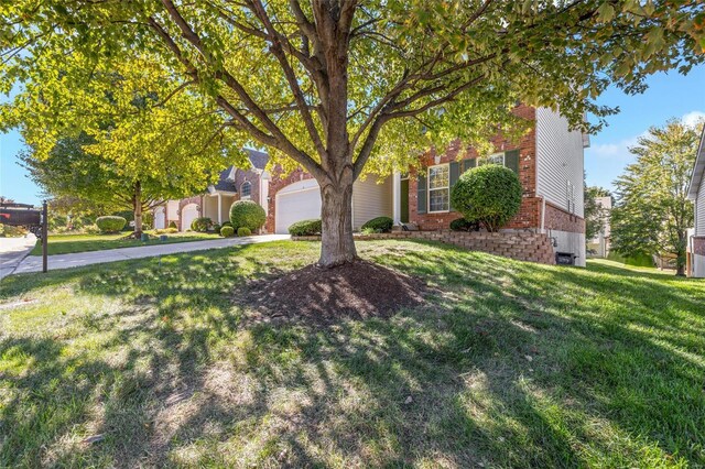 view of property hidden behind natural elements featuring a front lawn and a garage