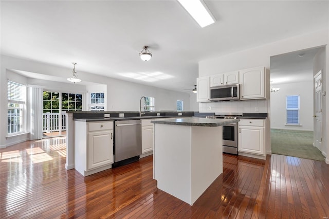 kitchen featuring a center island, stainless steel appliances, white cabinetry, and kitchen peninsula