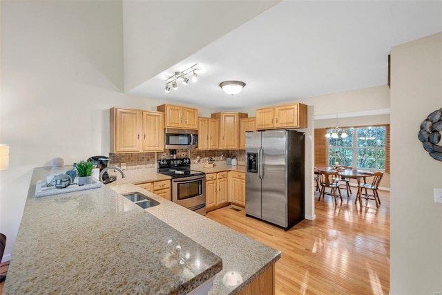 kitchen featuring light wood-type flooring, light stone counters, light brown cabinets, sink, and appliances with stainless steel finishes