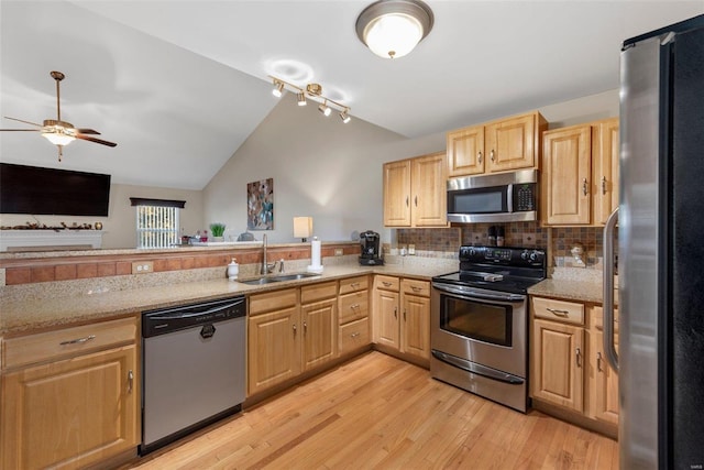 kitchen with lofted ceiling, sink, tasteful backsplash, stainless steel appliances, and light hardwood / wood-style floors