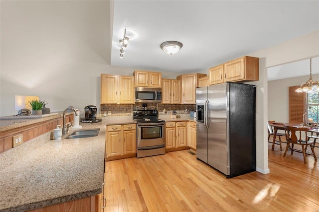 kitchen featuring light hardwood / wood-style floors, an inviting chandelier, pendant lighting, sink, and stainless steel appliances