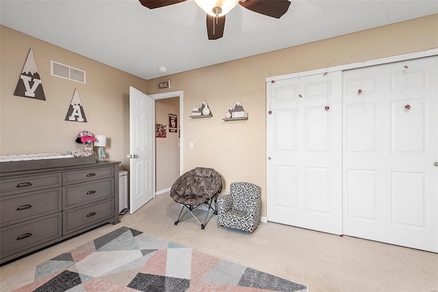 bedroom with ceiling fan, light colored carpet, and a closet