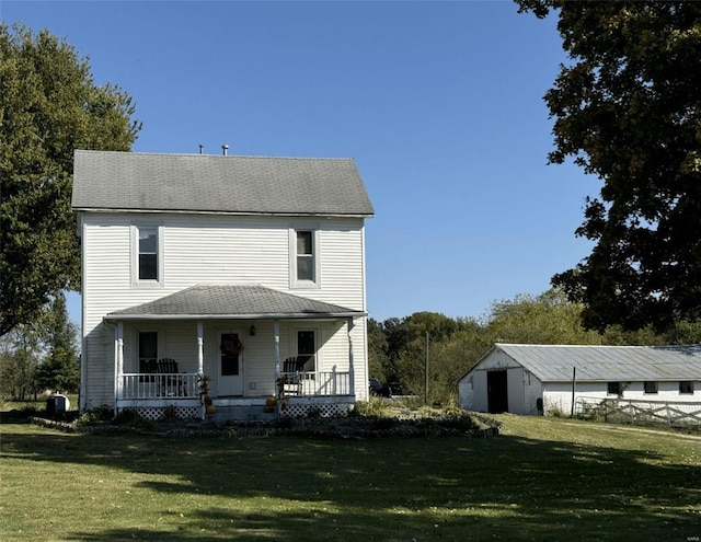 view of front of home with covered porch, a front yard, and an outdoor structure