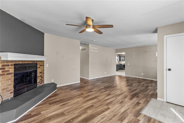 unfurnished living room with wood-type flooring, a fireplace, and ceiling fan