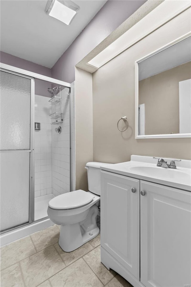 bathroom featuring tile patterned flooring, vanity, walk in shower, and toilet