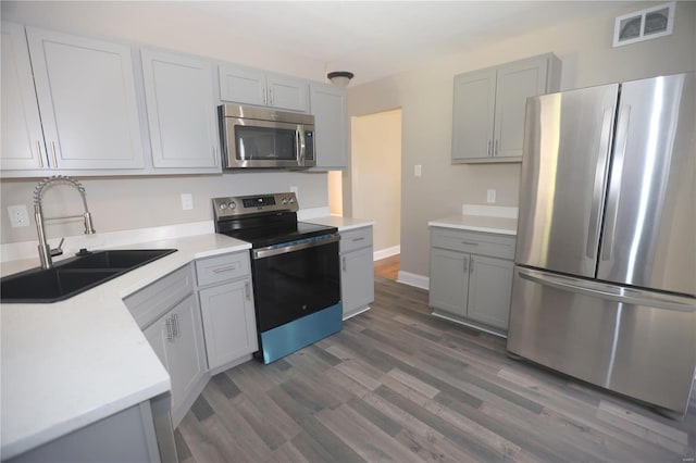 kitchen featuring stainless steel appliances, sink, dark hardwood / wood-style flooring, and gray cabinets