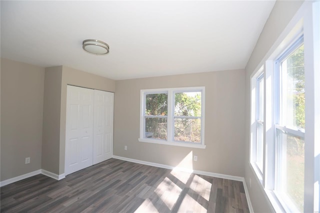 unfurnished bedroom with dark wood-type flooring and a closet