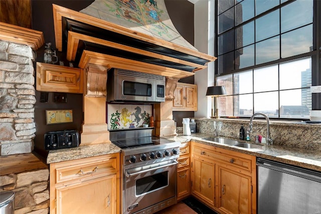 kitchen featuring light stone counters, stainless steel appliances, and sink