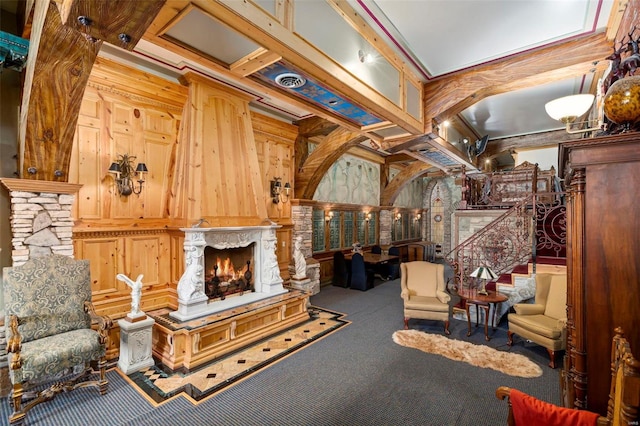 carpeted living room featuring beamed ceiling, crown molding, a fireplace, and wood walls