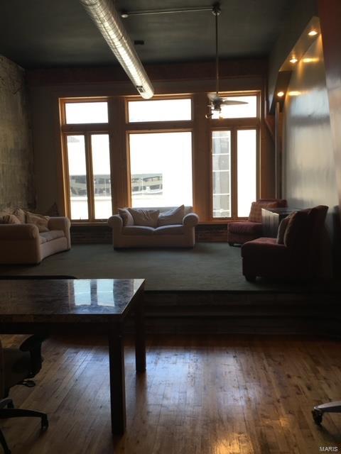 living room featuring ceiling fan, wood-type flooring, and a wealth of natural light