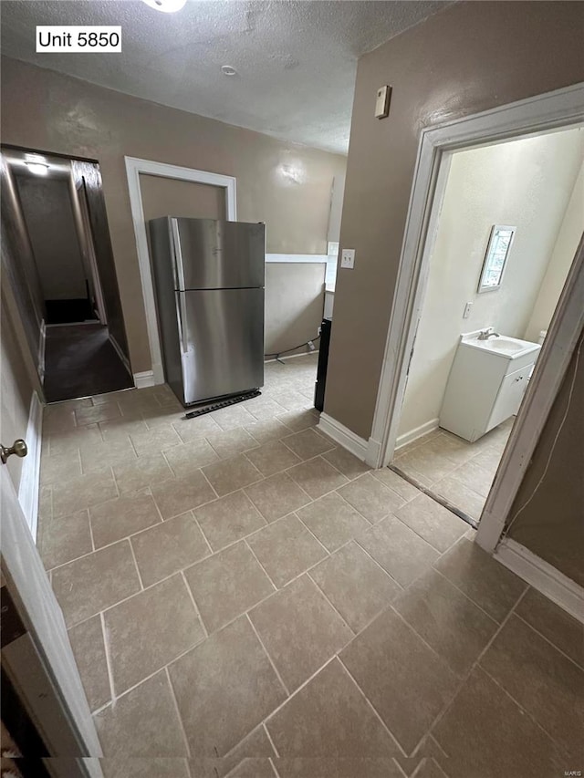 bathroom with a textured ceiling, sink, and tile patterned flooring