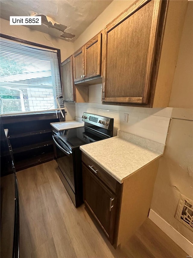 kitchen with black range with electric stovetop and light hardwood / wood-style flooring