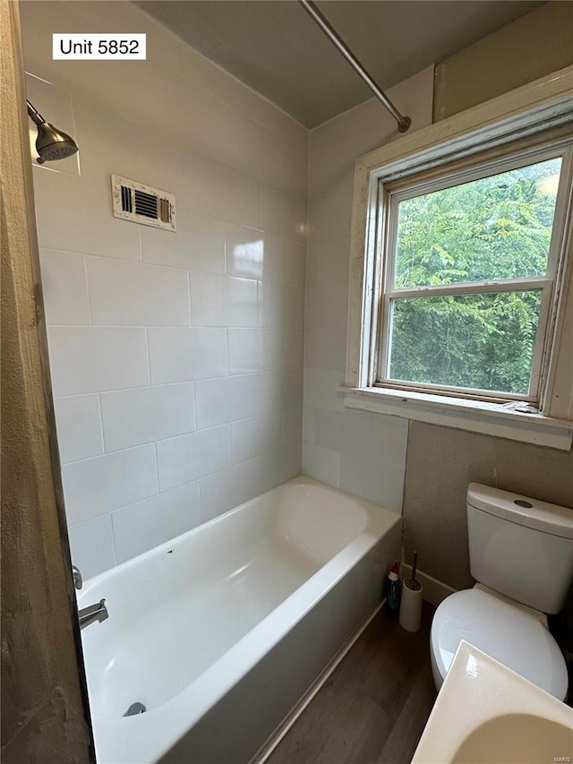 bathroom featuring toilet, hardwood / wood-style floors, and tiled shower / bath