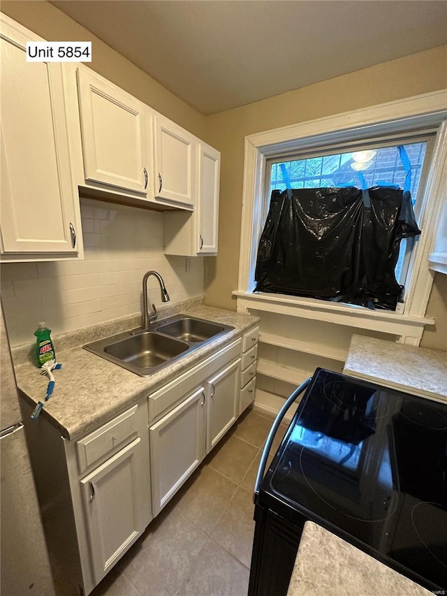 kitchen with white cabinetry, sink, black range with electric stovetop, and light tile patterned floors