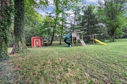 view of yard with an outbuilding, a playground, and a storage shed