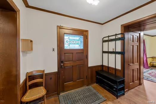 interior space with wood finished floors, a wainscoted wall, and ornamental molding