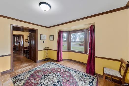 interior space with crown molding, wood finished floors, and baseboards