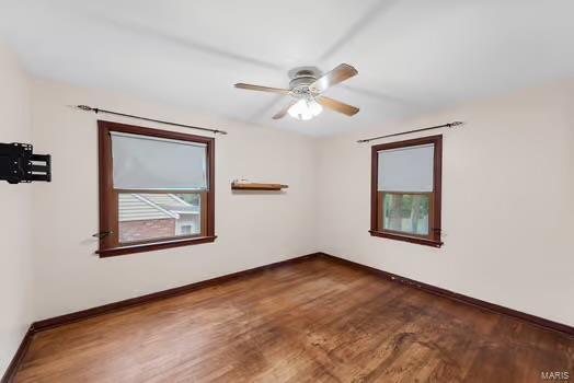 empty room with wood finished floors, a ceiling fan, and baseboards