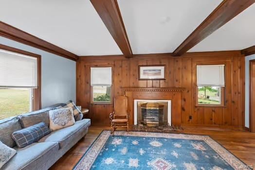 living room with wood walls, hardwood / wood-style floors, and beamed ceiling