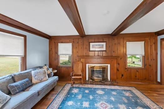 living room featuring wood walls, beam ceiling, and wood finished floors