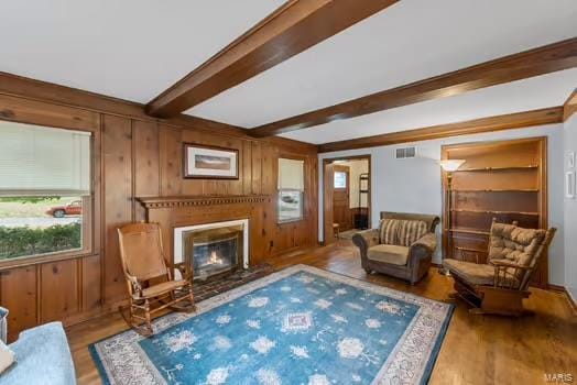 sitting room with wood walls, beamed ceiling, and wood-type flooring