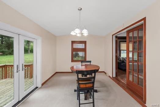 dining space with baseboards, light carpet, a notable chandelier, and french doors