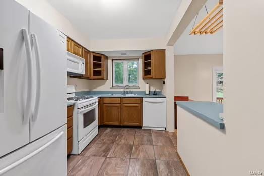 kitchen with a sink, brown cabinets, and white appliances