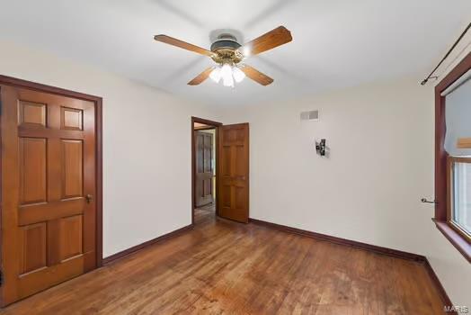 unfurnished room with baseboards, visible vents, wood finished floors, and ceiling fan