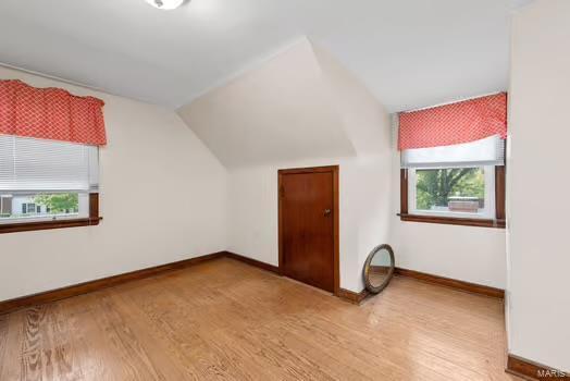 additional living space featuring baseboards, wood finished floors, and lofted ceiling