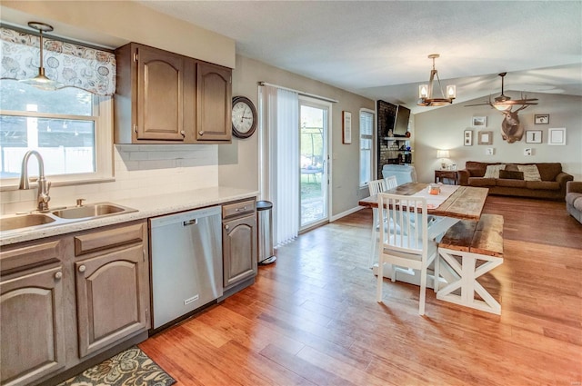 kitchen featuring tasteful backsplash, sink, light wood-type flooring, pendant lighting, and stainless steel dishwasher