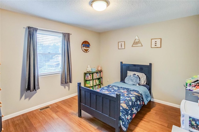 bedroom with hardwood / wood-style flooring and a textured ceiling