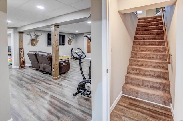 stairway with a drop ceiling and wood-type flooring