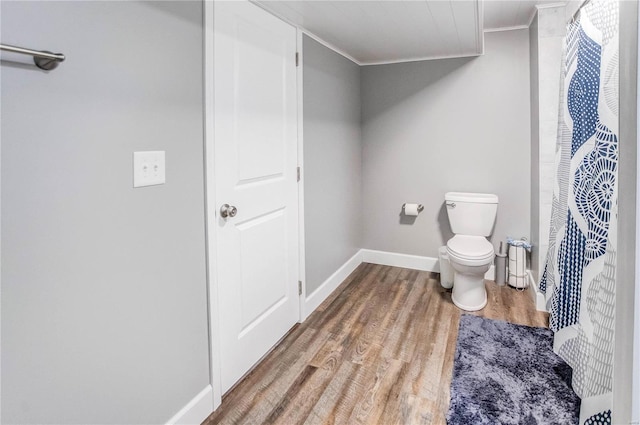 bathroom featuring toilet, ornamental molding, and wood-type flooring