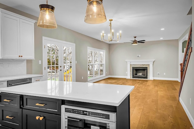 kitchen with white cabinetry, a fireplace, light hardwood / wood-style floors, and a center island