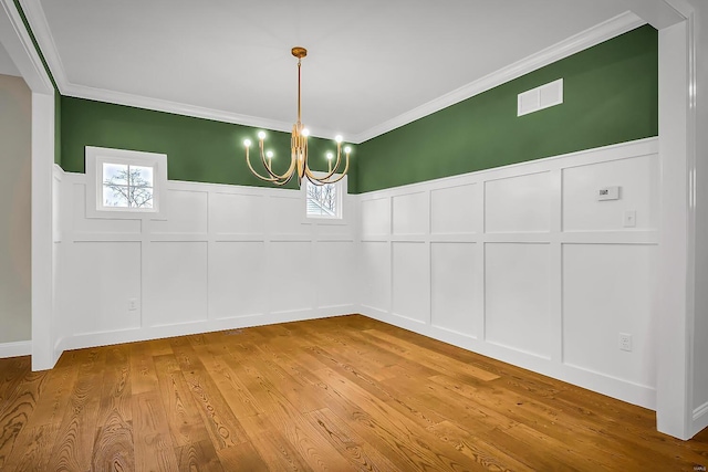 unfurnished dining area with crown molding, a healthy amount of sunlight, a chandelier, and light hardwood / wood-style floors