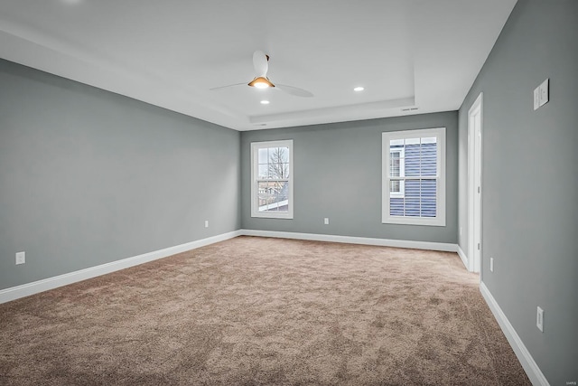 unfurnished room featuring a raised ceiling, carpet flooring, and ceiling fan