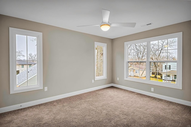 carpeted spare room featuring plenty of natural light and ceiling fan