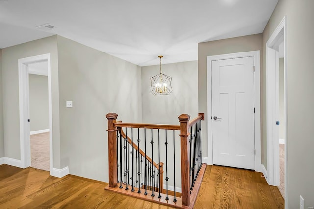 hall with wood-type flooring and a notable chandelier