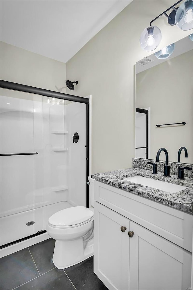 bathroom featuring tile patterned flooring, vanity, a shower with shower door, and toilet