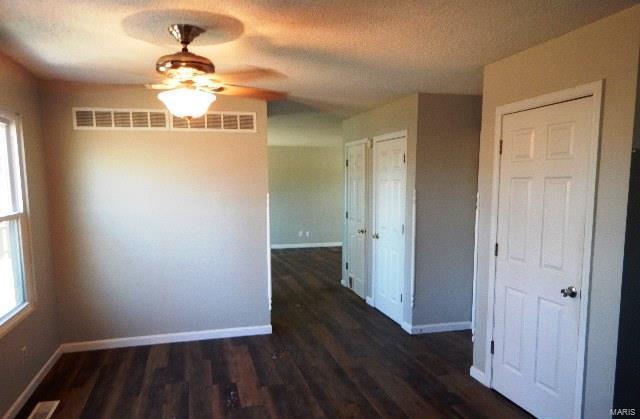 unfurnished dining area featuring a textured ceiling, dark hardwood / wood-style floors, and ceiling fan